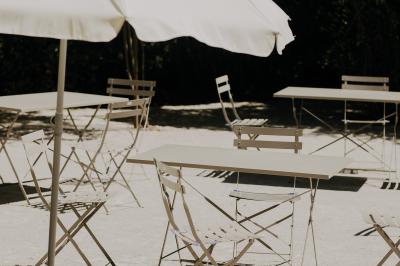 Allée de gravier bordée de rosiers roses en fleurs, entourée de pelouse et d'arbres en arrière-plan.