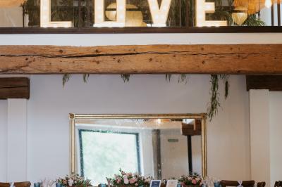 Allée de gravier bordée de rosiers roses en fleurs, entourée de pelouse et d'arbres en arrière-plan.