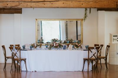 Allée de gravier bordée de rosiers roses en fleurs, entourée de pelouse et d'arbres en arrière-plan.