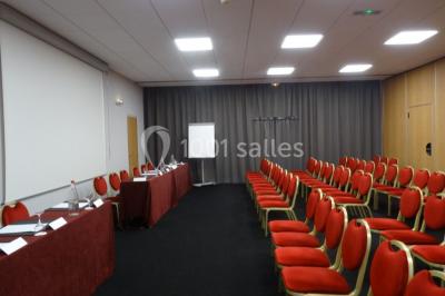 Salon lumineux avec canapé beige, table basse en bois, escalier, grande baie vitrée et vue sur un paysage extérieur.