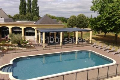 Salon lumineux avec canapé beige, table basse en bois, escalier, grande baie vitrée et vue sur un paysage extérieur.