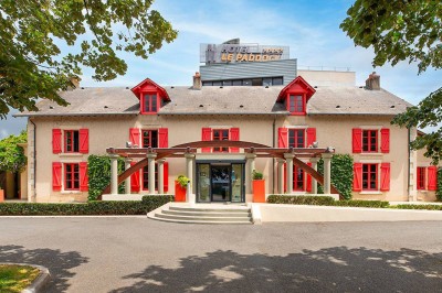 Salon lumineux avec canapé beige, table basse en bois, escalier, grande baie vitrée et vue sur un paysage extérieur.