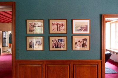 Salon lumineux avec canapé beige, table basse en bois, escalier, grande baie vitrée et vue sur un paysage extérieur.