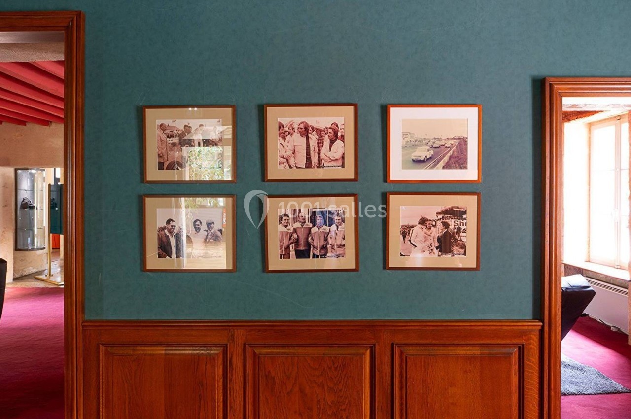 Mur décoré de six cadres photo alignés, dans une pièce aux murs bleus et boiseries en bas.