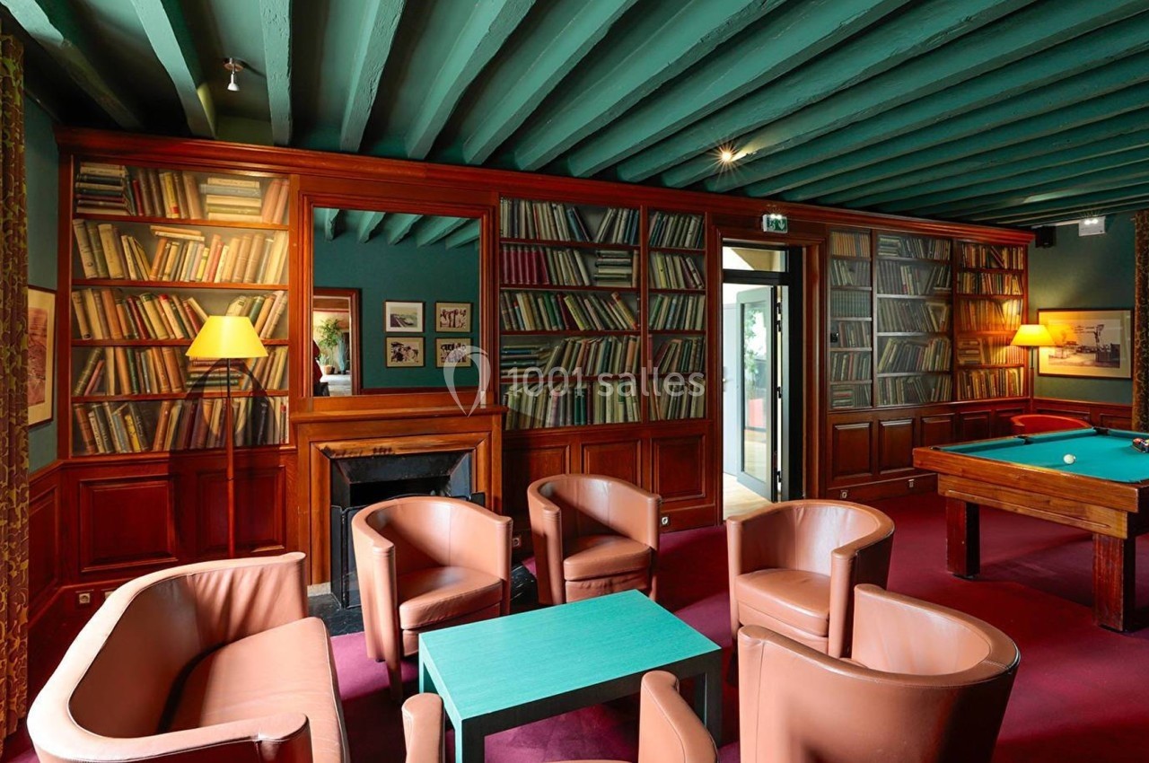 Salle avec des étagères remplies de livres, un billard, des fauteuils en cuir et un plafond peint en vert.