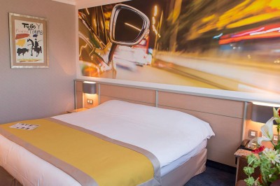 Salon lumineux avec canapé beige, table basse en bois, escalier, grande baie vitrée et vue sur un paysage extérieur.