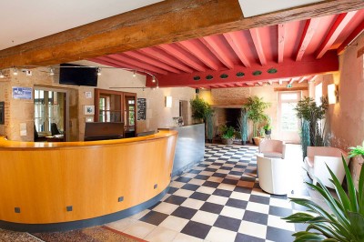 Salon lumineux avec canapé beige, table basse en bois, escalier, grande baie vitrée et vue sur un paysage extérieur.