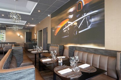 Salon lumineux avec canapé beige, table basse en bois, escalier, grande baie vitrée et vue sur un paysage extérieur.