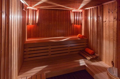 Salon lumineux avec canapé beige, table basse en bois, escalier, grande baie vitrée et vue sur un paysage extérieur.