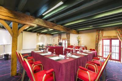 Salon lumineux avec canapé beige, table basse en bois, escalier, grande baie vitrée et vue sur un paysage extérieur.