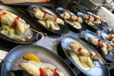 Baguette de pain posée sur un comptoir en bois, avec un four professionnel en arrière-plan dans une cuisine.