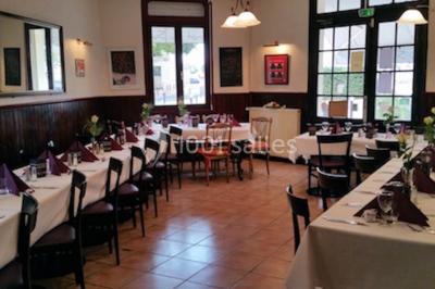 Baguette de pain posée sur un comptoir en bois, avec un four professionnel en arrière-plan dans une cuisine.