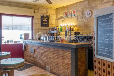 Baguette de pain posée sur un comptoir en bois, avec un four professionnel en arrière-plan dans une cuisine.