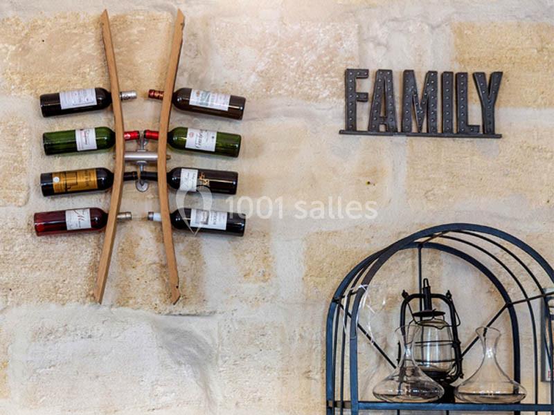 Porte-bouteilles mural en bois avec plusieurs bouteilles de vin, décoré d'une inscription ’Family’ sur un mur en pierre.