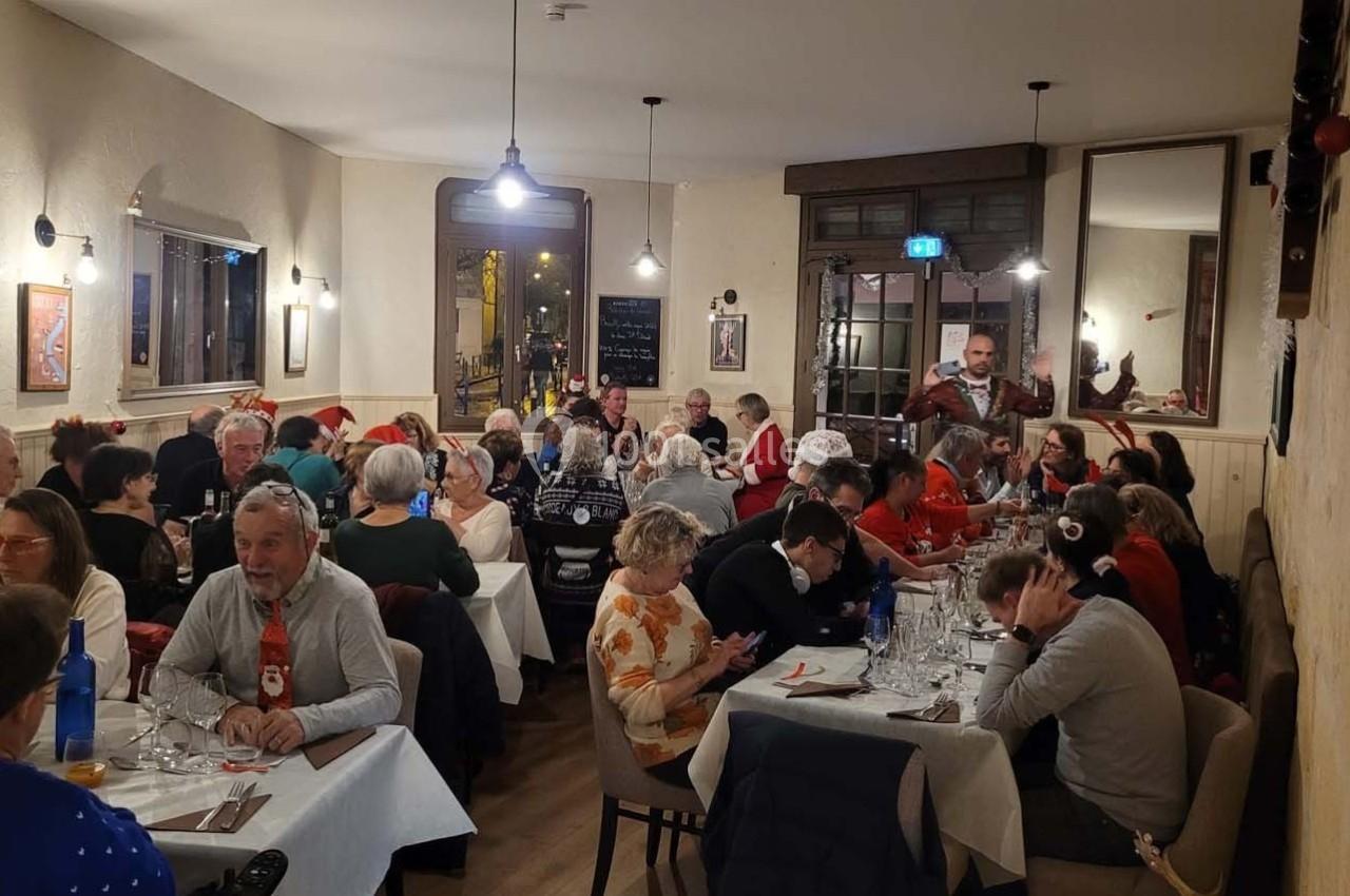 Des personnes d'âges variés dînent dans un restaurant chaleureux, décoré pour une ambiance conviviale.