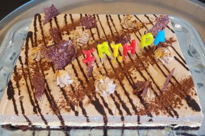 Baguette de pain posée sur un comptoir en bois, avec un four professionnel en arrière-plan dans une cuisine.