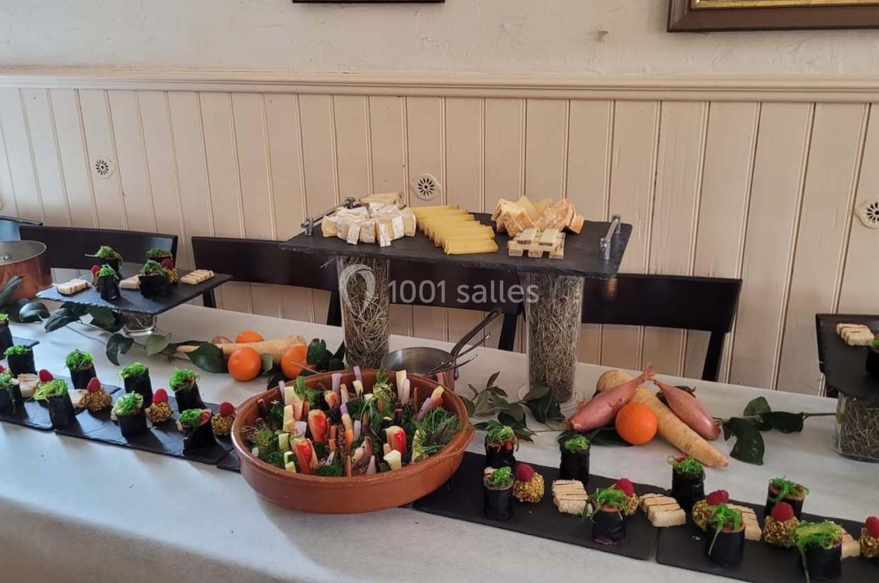 Buffet composé de fromages, légumes, et amuse-bouches variés disposés sur une table décorée.