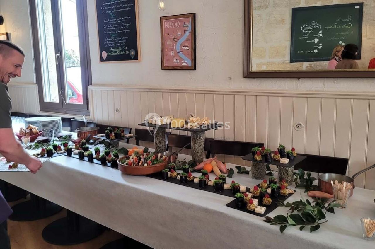 Table garnie de plats variés et colorés dans un restaurant, avec un homme souriant ajustant la présentation.