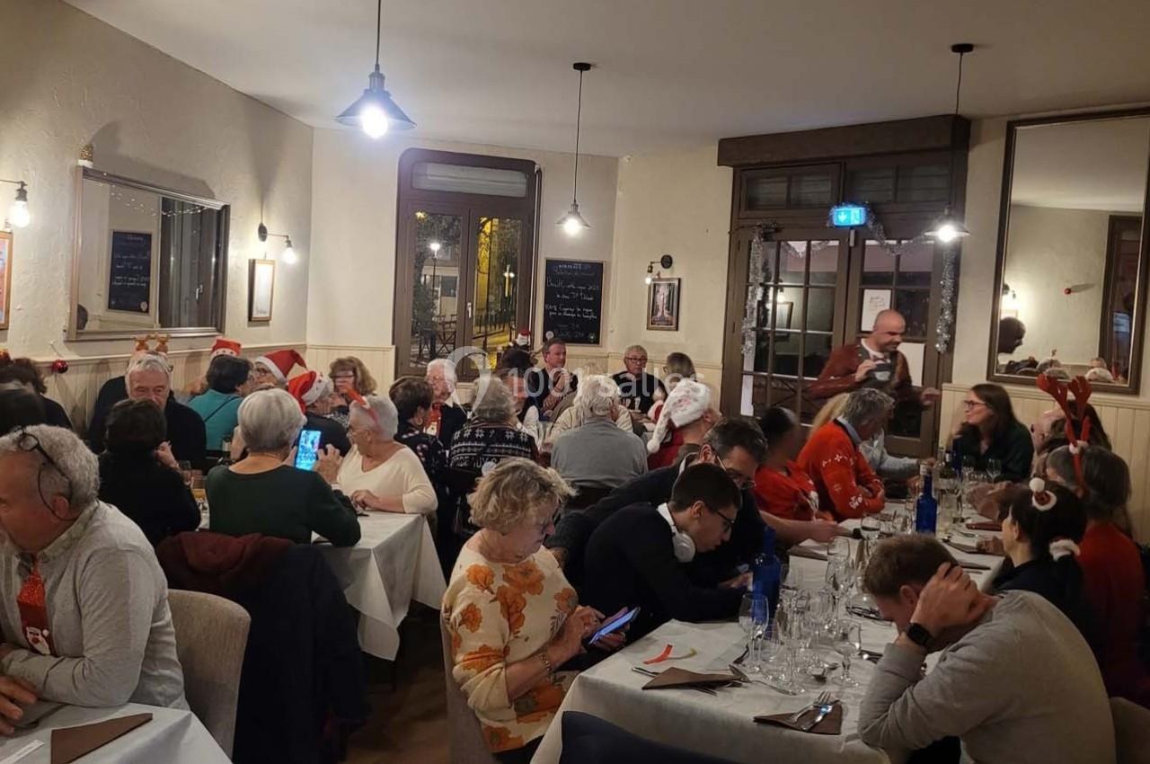 Groupe de personnes d'âges variés partageant un repas dans un restaurant chaleureux, décoré pour les fêtes.