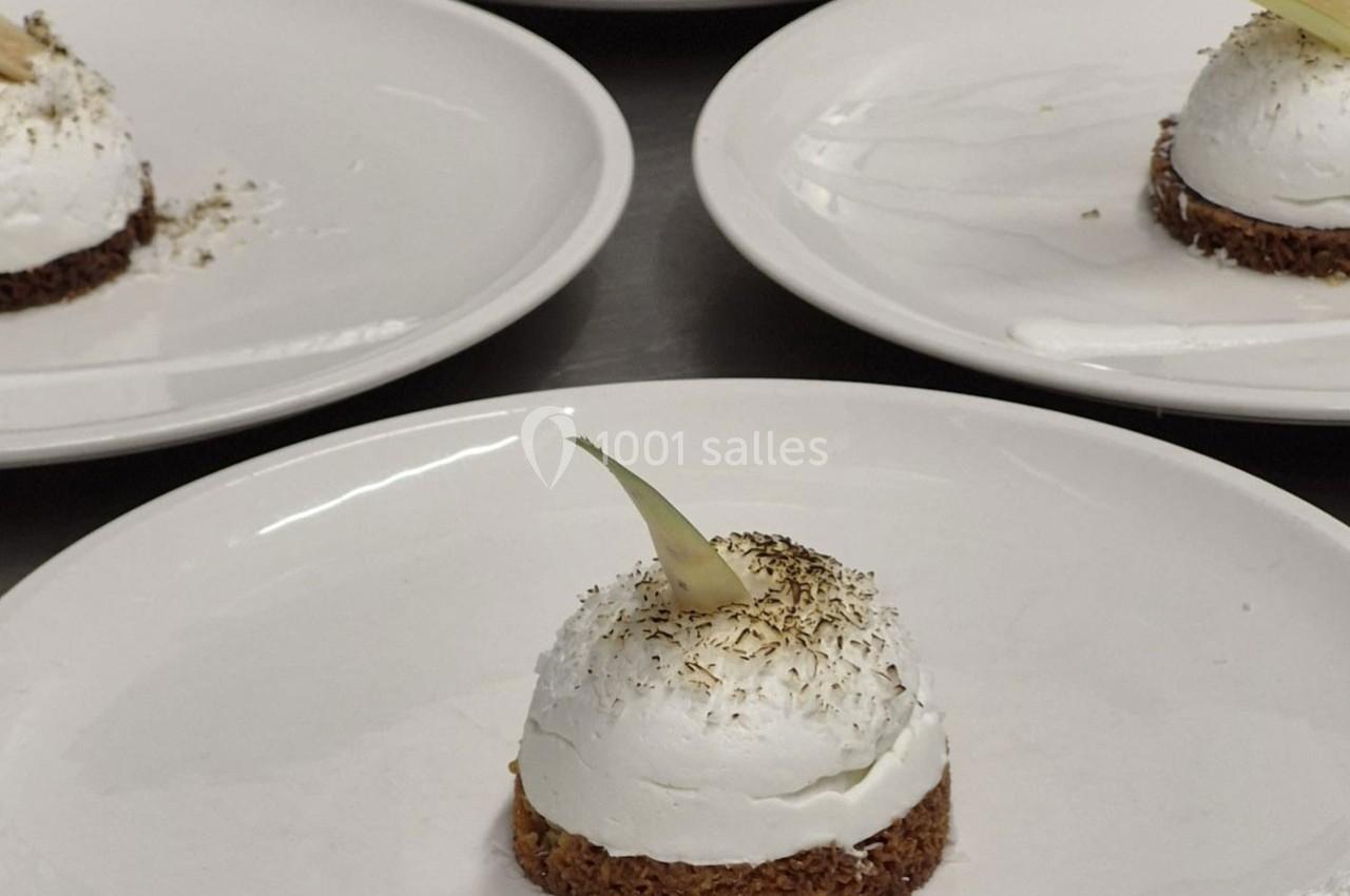 Dessert individuel composé d'une base croustillante, d'une mousse blanche et d'une décoration fine sur le dessus.