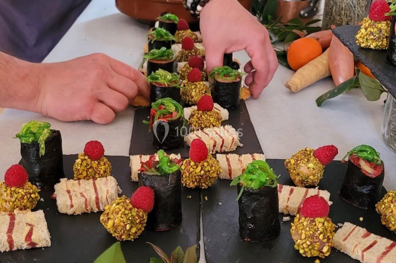 Assiette garnie de bouchées variées : makis, tranches de pain garnies et boulettes enrobées de pistaches.