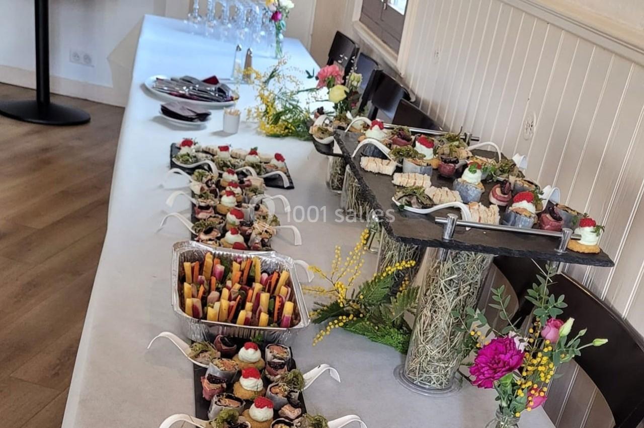 Buffet de desserts variés et colorés disposés sur une table décorée de fleurs dans une salle lumineuse.