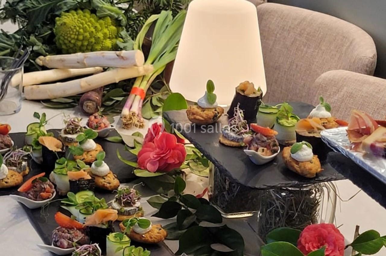 Plateau de bouchées apéritives variées avec légumes frais en arrière-plan et décoration florale.