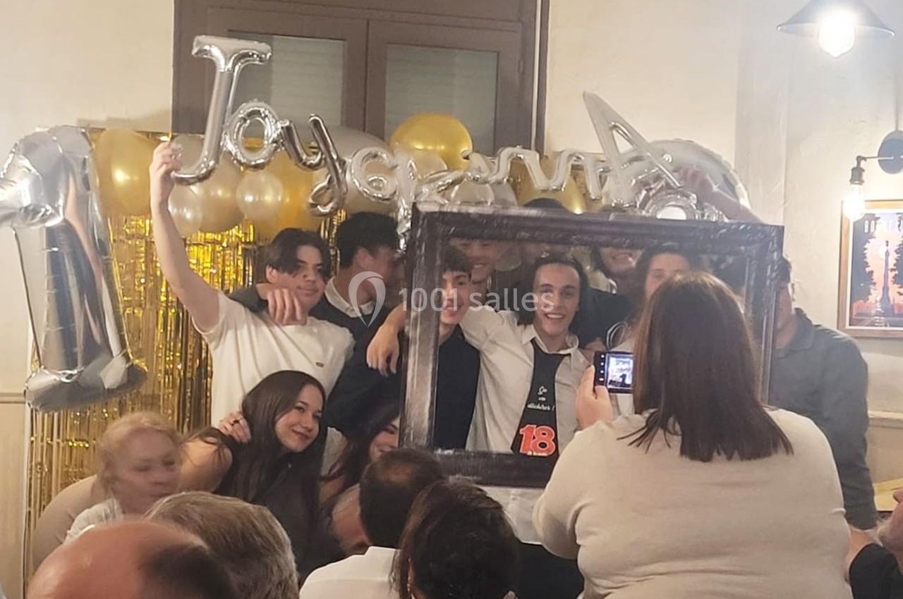 Un groupe de jeunes pose avec un cadre photo devant des ballons et une décoration festive lors d'une célébration.