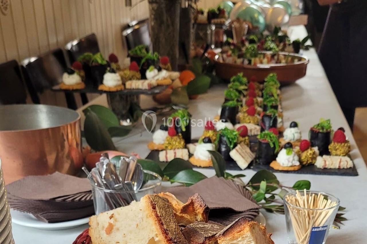 Buffet avec pain, desserts variés, verrines et décorations végétales sur une table dressée pour un événement.