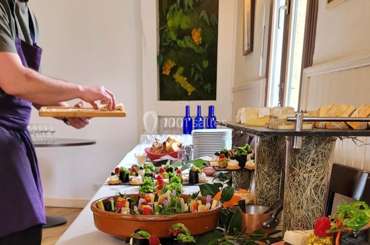 Un buffet garni de plats variés et colorés, avec un serveur disposant des assiettes sur une table.