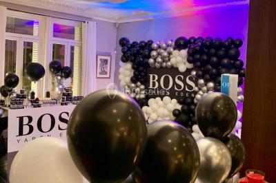 Table ronde en métal noir avec chandelier et chaises, placée sur un balcon avec vue sur une façade d'immeuble haussmannien.