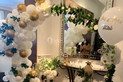 Table ronde en métal noir avec chandelier et chaises, placée sur un balcon avec vue sur une façade d'immeuble haussmannien.