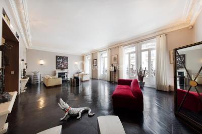 Table ronde en métal noir avec chandelier et chaises, placée sur un balcon avec vue sur une façade d'immeuble haussmannien.