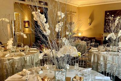 Table ronde en métal noir avec chandelier et chaises, placée sur un balcon avec vue sur une façade d'immeuble haussmannien.