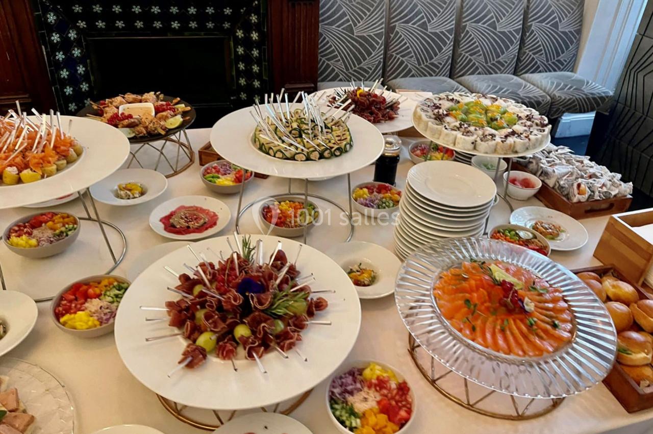 Buffet varié avec des plats froids, brochettes, sushis, saumon fumé et assortiments de légumes colorés.