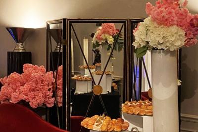 Table ronde en métal noir avec chandelier et chaises, placée sur un balcon avec vue sur une façade d'immeuble haussmannien.