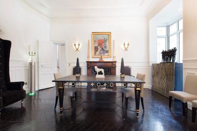 Table ronde en métal noir avec chandelier et chaises, placée sur un balcon avec vue sur une façade d'immeuble haussmannien.