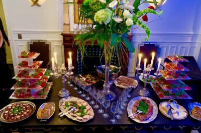 Table ronde en métal noir avec chandelier et chaises, placée sur un balcon avec vue sur une façade d'immeuble haussmannien.