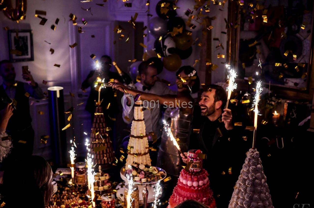 Des invités célèbrent dans une ambiance festive avec des desserts élaborés, des confettis et des feux de Bengale.