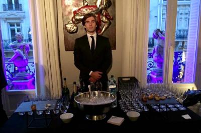 Table ronde en métal noir avec chandelier et chaises, placée sur un balcon avec vue sur une façade d'immeuble haussmannien.