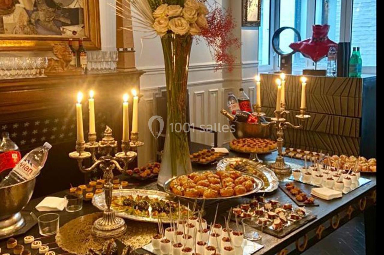 Buffet élégant avec chandeliers, desserts variés, fleurs et boissons disposés sur une table dans un cadre raffiné.