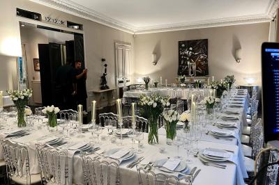 Table ronde en métal noir avec chandelier et chaises, placée sur un balcon avec vue sur une façade d'immeuble haussmannien.