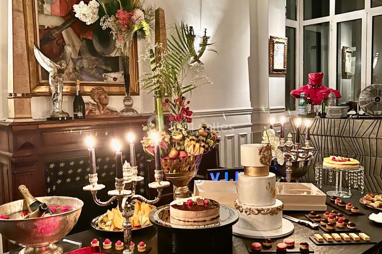 Table élégamment dressée avec des desserts variés, bougies allumées et décorations florales dans un intérieur raffiné.