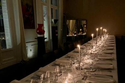 Table ronde en métal noir avec chandelier et chaises, placée sur un balcon avec vue sur une façade d'immeuble haussmannien.