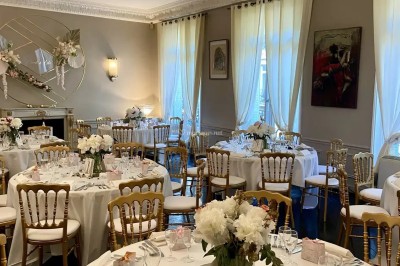 Table ronde en métal noir avec chandelier et chaises, placée sur un balcon avec vue sur une façade d'immeuble haussmannien.