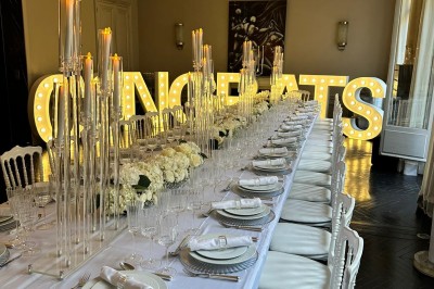 Table ronde en métal noir avec chandelier et chaises, placée sur un balcon avec vue sur une façade d'immeuble haussmannien.