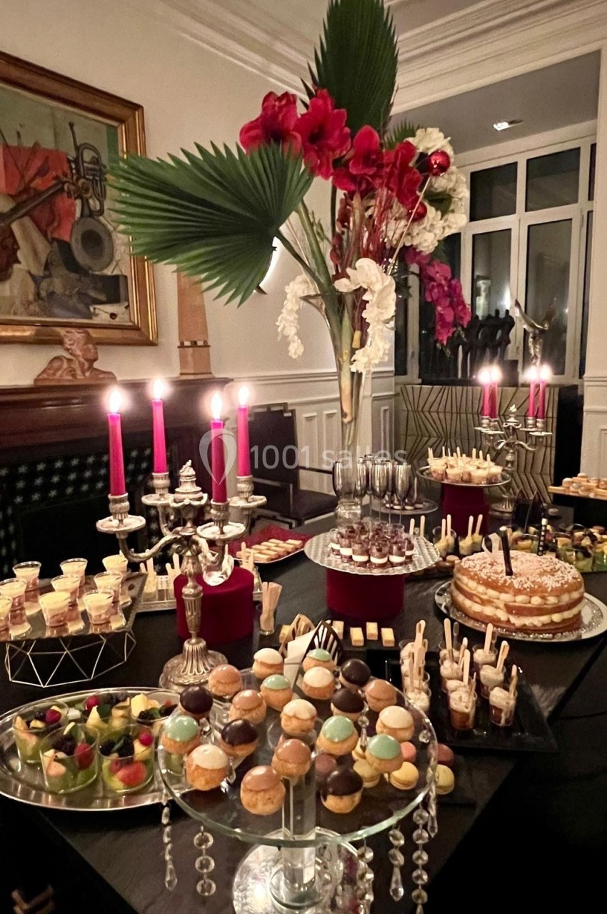 Table garnie de desserts variés, bougies allumées et décoration florale dans un intérieur élégant.