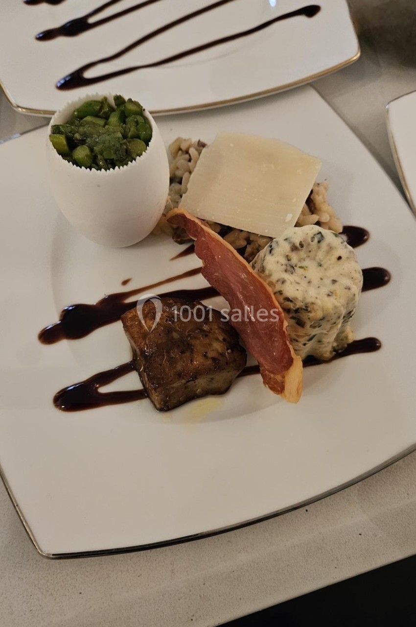 Assiette gastronomique avec foie gras, tranche de jambon, purée, légumes verts et sauce balsamique.