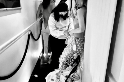 Table ronde en métal noir avec chandelier et chaises, placée sur un balcon avec vue sur une façade d'immeuble haussmannien.