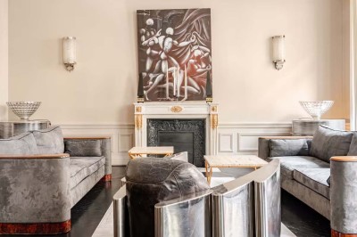 Table ronde en métal noir avec chandelier et chaises, placée sur un balcon avec vue sur une façade d'immeuble haussmannien.